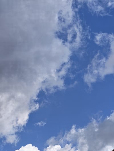 The image depicts a sky with scattered clouds. The blue sky is visible in the lower right quadrant, with several white and gray clouds occupying the rest of the frame. The clouds vary in density, with some appearing wispy and translucent, while others are thicker and more opaque. There are no people, buildings, or any other discernible objects or structures in the image. The location in the city of Mayrtup, Russia cannot be determined from the provided image.
