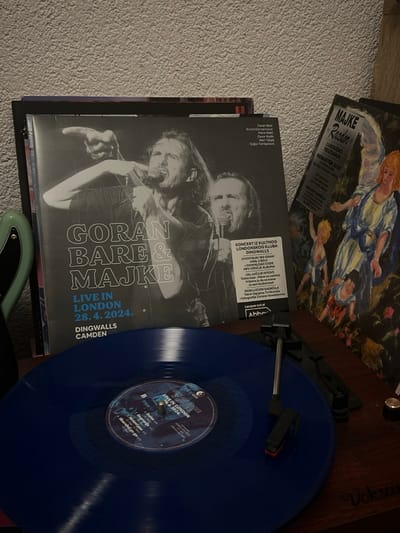 The image showcases vinyl records and their covers. There are two records, one blue and one obscured. The blue vinyl features "Ocean Dark," "Live in London 28.4.2024." with track titles listed. There are also the album covers of "Goran Bare & Majke Live in London 28.4.2024" and "Majke Razdor." The image also shows details like "Koncert iz kultnog londonskog kluba Dingwalls." and "Luksuzno Reizdanje Remaster 2023." This suggests the records are live recordings and reissued material.