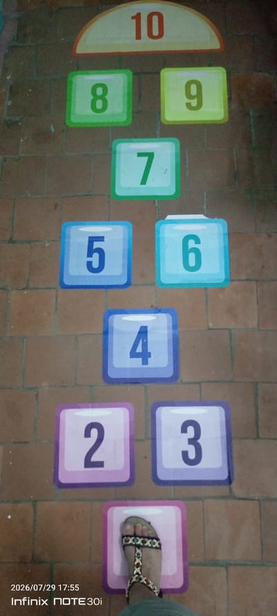 In Langepas, Russia, a hopscotch game is laid out on a brick-like floor. The numbers 10, 9, 8, 7, 6, 5, 4, 3, and 2 are displayed in colorful squares, arranged in a sequence. A person's foot wearing a sandal is positioned on the square marked with the number 1. The image is dated 2026/07/29 at 17:55, as indicated by the timestamp from an Infinix NOTE 30i phone.