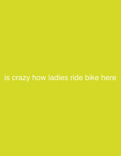The image displays white sans-serif text centrally aligned on a solid, vibrant yellowish-green background. The text reads: "is crazy how ladies ride bike here". The term "here" refers to the city of Igarra, Nigeria, providing context for the observation regarding women cycling. No other visual elements, individuals, objects, or activities are present within the frame, which is solely composed of the colored background and the overlaying text.