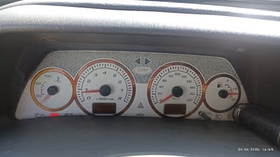 This media file captures a close-up view of a car's dashboard, featuring multiple gauges. On the left is a temperature gauge, with a needle pointing between 50 and 90 degrees Celsius, indicating the engine temperature. To its right, an odometer shows a reading of 15144. Next to the odometer is the tachometer, with the needle resting at 0, suggesting the engine is not running or is idling at a very low RPM. The speedometer is to the right of the tachometer, with its needle also at 0. A fuel gauge is positioned on the far right, showing the fuel level to be just below the 1/2 mark. Below the main gauges, there are several indicator lights, including what appears to be an oil pressure warning light illuminated in red. A small digital display below the tachometer likely shows trip information. The dashboard itself is dark, with the gauges having white faces and orange accents. The overall setting is inside a vehicle, likely during the daytime given the lighting. The date stamp at the bottom right of the image indicates "30.06.2026 14:49", and the location context provided is "Rossosh, Russia". No people are visible in the frame. The overall impression is a functional view of the car's internal instrumentation.