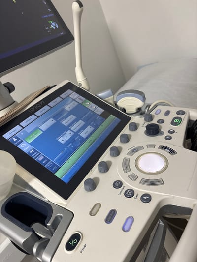 A close-up shot focuses on the control panel of a GE LOGIQ P7 ultrasound machine. The image includes the machine's touchscreen interface, several buttons and knobs, and a probe. The screen displays various imaging parameters in both English and Spanish. The presence of the ultrasound machine suggests a medical setting. There are no people visible in the shot. The specific location within Medellín, Colombia, cannot be determined from the image.
