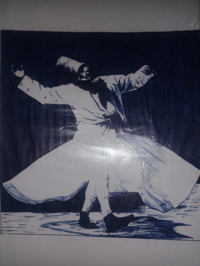 This is a sketch of a whirling dervish in Gulbag, Uzbekistan. The dervish is a man wearing a traditional white robe and a tall, conical hat, with his arms outstretched as he spins. The robe flares out around him, creating a sense of dynamic movement. The background is a dark blue, with vertical lines suggesting a dimly lit or curtained space. The floor is depicted with a series of horizontal strokes, indicating a textured or uneven surface. The overall impression is one of spiritual ecstasy and graceful motion.
