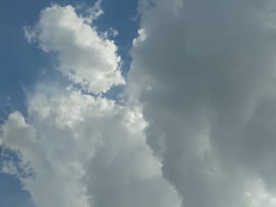 A broad, high-angle shot captures a sky filled with a mixture of clouds and patches of blue sky. The clouds are predominantly white and fluffy, with some areas appearing denser and darker, suggesting a potential shift in weather. The lighting indicates it is daytime, with sunlight filtering through the clouds. The image does not contain any discernible urban elements or human presence, making it impossible to determine the specific location within Osh City, Kyrgyzstan, or any associated activity.