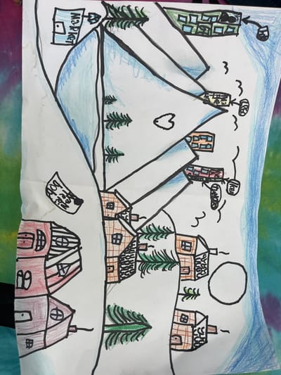The image is a colorful, hand-drawn illustration depicting a stylized mountain landscape with a village. The drawing is on white paper and shows several elements:

**Mountains:** Two large, triangular shapes represent snow-capped mountains, colored in light blue with black outlines.

**Buildings:**
*   **Upper area:** Several buildings are drawn. One prominently features "MS POKET" written in blue text, appearing to be a market or store. Another building is green with multiple square windows. A red and brown building has a similar window pattern.
*   **Lower area:** A cluster of houses with brown and red coloring and black outlines are depicted. These houses have windows and some show chimneys with smoke. One larger red house dominates the bottom left.

**Nature Elements:** Green pine trees are scattered throughout the scene, especially around the houses and on the slopes of the mountains. A large, incomplete circle in the lower right could represent the sun or moon.

**Other Details:**
*   Wavy black lines are used as decorative elements, possibly indicating wind or movement.
*   A torn piece of paper with handwritten text that appears to say "HOBI" and "NEX" is attached to the left side of the drawing.
*   Arrows connect some of the buildings, suggesting a map or directional guidance.
*   The background of the drawing paper shows a tie-dye pattern with purple, blue, and green colors, indicating the surface on which the drawing is placed.

**Location:** The drawing does not contain any specific geographical markers or elements that would place it in the city of Čačak, Serbia. It is a general representation of a mountain village.