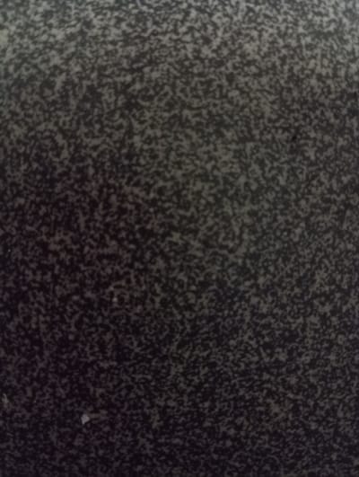 The image shows a close-up, abstract view of a speckled surface, possibly granite or a similar material, with a dark gray background and irregular, lighter gray and black speckles. There are no discernible people, objects, or actions. The texture appears granular and uneven. The image does not contain any elements that can be used to identify a specific location within Hlynytsi, Ukraine.