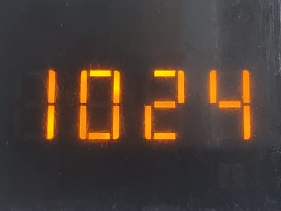 The image displays a digital readout of the number "1024" illuminated in orange against a dark, textured background. The numbers are blocky and appear to be part of an electronic display, possibly on a device or instrument. The background is a dark, matte surface with some slight imperfections or dust particles visible. There are no people or any identifiable landmarks or environmental features within the frame to suggest a specific location in Temirtau, Kazakhstan. The image is a close-up of the digital display.