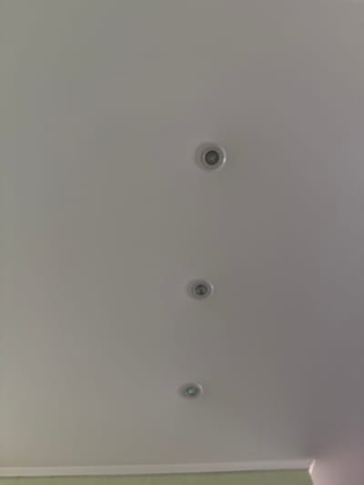 The image shows a white ceiling with three recessed lights. The lights are circular and appear to be of the same design. The ceiling is evenly lit, suggesting artificial lighting. There is a subtle color variation at the bottom of the image, indicating the presence of a wall or trim. The scene is devoid of any people or other discernible objects. The location, Levkovo, Russia, provides context for the setting, implying an indoor residential or commercial space. The image is taken from a low angle, looking upwards at the ceiling.