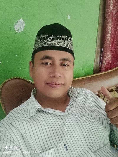A man wearing a black and silver Muslim cap is giving a thumbs-up. He has a light-skinned complexion and wears a white and blue striped shirt. He's sitting in what appears to be a chair, with a light brown and ornate backrest. The background consists of a lime green wall with a white smudge and a red curtain. The image includes a watermark at the bottom left corner with text "vivo y19s".