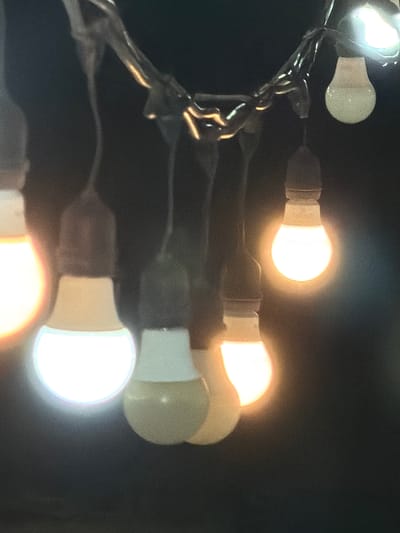 The image shows a string of light bulbs against a dark background. The bulbs are of a standard shape, with a round, opaque diffuser. Some of the bulbs are illuminated, emitting a warm, orange-yellow light. The string connecting the bulbs appears to be made of a twisted wire. The location is unknown.
