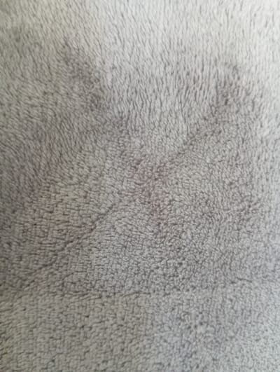 The image is a close-up, overhead shot of a gray, plush fabric. The texture is soft and appears to be a type of faux fur or fleece. The fibers are short and densely packed, creating a slightly uneven surface with subtle variations in light and shadow due to the direction of the pile. There are no people, objects, actions, or interactions visible. The image depicts only the fabric. The provided information about Hlynytsi, Ukraine is not reflected in the visual content of the image.