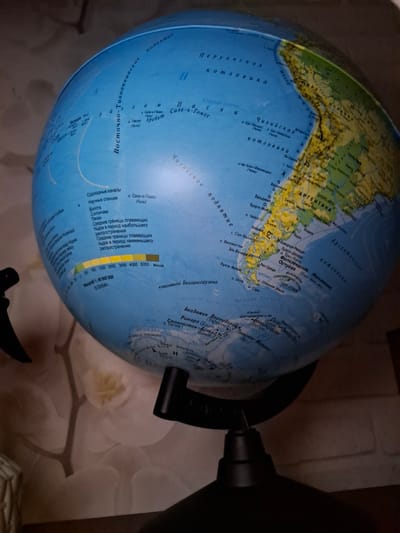 The image shows a globe with South America facing the viewer. The Pacific Ocean is visible on the left and the Atlantic on the right. Parts of North America and Antarctica are visible as well. The globe rests on a stand. The scale on the globe indicates a scale of 1:40,000,000. Text on the globe is in Russian.
The location is not in the city of Amzya, Russia. The location is not visible.