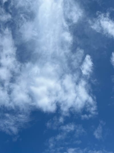 This media file depicts a sky with scattered clouds against a deep blue background. The clouds are predominantly white and wispy, with some appearing denser and more substantial than others. They are illuminated from above, suggesting it is daytime. The overall impression is of a pleasant, possibly breezy day, with the clouds adding texture and visual interest to the expanse of blue. There are no people or objects visible, and no text is present in the image. The setting is an outdoor scene focused solely on the sky.