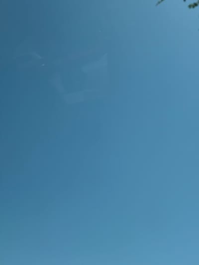 A clear blue sky is visible, with faint clouds and what appears to be the reflection of something in the upper left quadrant of the image. The top right corner shows a hint of green foliage. The image is oriented vertically. There is no discernible location within the city of Southlake, United States of America.