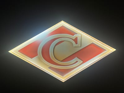 A sign displaying the letter "C" is centered in a dark, featureless environment. The sign is rhombus-shaped and appears to be illuminated from behind, casting a warm glow. The letter "C" is three-dimensional, rendered in a metallic or polished material, and is positioned prominently within the rhombus. The rhombus itself has layers with red and gold-colored elements. The overall presentation suggests a logo or emblem, possibly for a business or organization. The image does not contain any identifiable urban features or indicate a specific location within Protasovo, Russia.