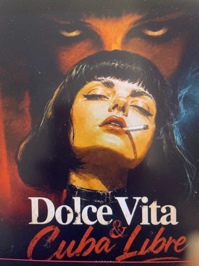 This is a close-up, rotated image of a painting or illustration that appears to be a book cover. The main subject is a woman with dark hair and closed eyes, her head tilted back slightly. She is smoking a cigarette, with smoke gently rising around her face. Her lips are painted a vibrant red, and her expression suggests a state of relaxation or perhaps melancholy.
The woman's skin is rendered in warm, golden tones, contrasted by the dark background. To the right of the woman's face, prominent text in white and red is visible. The white text, stacked vertically and oriented from bottom to top, reads "Dolce Vita". Below this, the "&" symbol appears, followed by red script that reads "Cuba Libre". This combination of text and imagery evokes a sense of nostalgia, possibly referencing the iconic Italian film "La Dolce Vita" and the classic cocktail.
The overall mood is dramatic and cinematic, with strong lighting that highlights the woman's features. While no specific time of day or weather is discernible, the setting and imagery suggest a sophisticated, possibly nighttime scene associated with leisure and indulgence. The location context of Punta Ala, Italy, adds to this atmosphere of Italian glamour and relaxation.