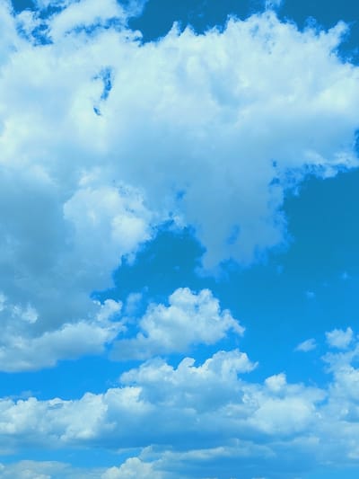 The image is a photograph of a bright blue sky filled with various types of clouds. The clouds range from fluffy, white cumulus clouds to more scattered, wispy cirrus clouds. Some clouds are dense and appear to be casting shadows, while others are translucent, allowing the blue sky to show through. The overall impression is of a clear day with dynamic cloud formations. There are no buildings, people, or any other man-made objects visible in the image, suggesting it was taken from a vantage point where only the sky is in view, or in an open, natural environment with no urban structures. The image does not provide any specific information about the location in the city of Unknown, Bulgaria, as there are no identifiable landmarks or context clues.