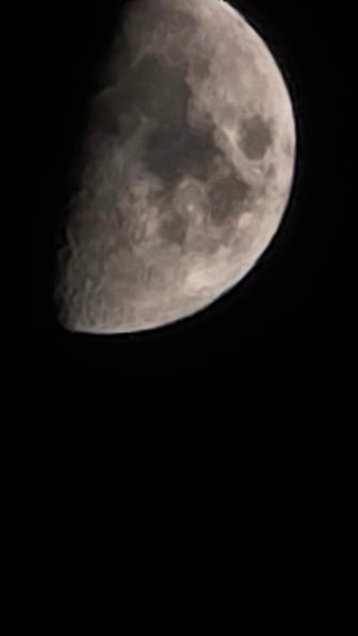 The image shows a close-up of the moon, partially illuminated. The moon has a textured surface with visible craters and maria, rendered in shades of grey and white. The background is completely black, indicating a night sky with no other celestial bodies or atmospheric phenomena visible. There are no man-made objects or any signs of human presence. The image appears to be a photograph taken with a telescope or a camera with a telephoto lens, focusing solely on the moon. No specific location, including Oyskhara, Russia, can be identified from the image content.