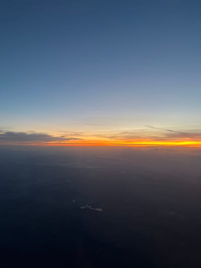 The image shows a sunset. The left side of the image is a light blue sky, transitioning to orange and yellow towards the center, indicating the sunset. The right side is a dark, almost black, area, likely representing the night sky or the horizon. There are some clouds in the sunset area. It is not possible to determine the location as Ettelbruck, Luxembourg from this image.