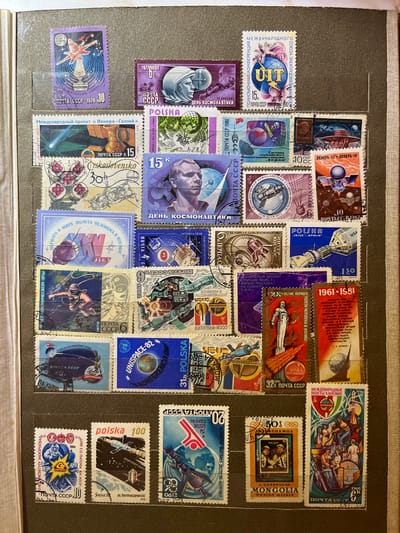 The image is a close-up, overhead view of a stamp album page featuring numerous postage stamps primarily related to space exploration. The stamps are arranged in rows and columns on a light brown textured background, which appears to be the interior of the album. Many of the stamps are from the USSR, with others from Poland, Czechoslovakia, and Mongolia.
Thematically, the stamps depict rockets, astronauts, spacecraft, celestial bodies like the Earth and Moon, and symbols of international cooperation in space. Some stamps feature portraits of cosmonauts or scientists, while others illustrate specific space missions or technological achievements. Text on the stamps is in Russian, Polish, and English.
Specific details visible on the stamps include:
* A stamp with a purple background showing a rocket launching from Earth, with the text "ПОЧТА СССР - 1978 - 10" and "КОСМИЧЕСКАЯ СВЯЗЬ".
* A stamp with a purple background depicting a close-up of an astronaut's helmet, with the text "1977г. КОСМОНАВТИКИ" and "ПОЧТА СССР".
* A stamp with a blue and white design showing a globe being held by a hand, with "UIT" prominently displayed and text indicating an international conference.
* A stamp from Czechoslovakia showing a satellite with the text "MEZINARODNI PROJEKT «VENERA-GALLEN»".
* A stamp with a blue background depicting a cosmonaut in space with a tethered cable, with "1972 КОСМИЧЕСКОЙ ЭРЫ" and "ПОЧТА СССР 6".
* A stamp with a blue background featuring a satellite orbiting Earth, with "UNISPACE-82" and "POLSKA".
* A stamp from Mongolia showing two astronauts in helmets, with "J. GURRAGCHA" and "MONGOLIA".
* A stamp with a red and white design depicting people and spacecraft against a backdrop of Earth and stars, with "МЕЖДУНАРОДНЫЕ ПОЛЕТЫ В КОСМОС" and "ПОЧТА СССР 6".
There are no people, objects, or environmental features visible in the image that are outside of the postage stamps and the album page. The image does not provide any information about the city of Kramatorsk, Ukraine.