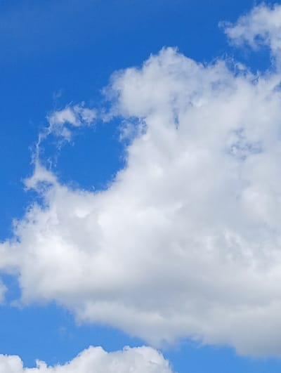 The image is a close-up, low-angle photograph of a bright blue sky filled with fluffy white cumulus clouds. The clouds are dense and textured, with some areas appearing more opaque and others more translucent, allowing hints of the blue sky to show through. The lighting suggests it is daytime, likely with the sun positioned above and slightly behind the viewer, casting a soft illumination on the clouds. There is no indication of any specific location within the city of Вясейскі сельскі Савет, Belarus, or any discernible man-made structures or natural landscapes apart from the sky and clouds. The image is purely focused on the atmospheric phenomenon.