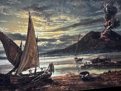 This image is a detailed depiction of a dramatic volcanic eruption occurring near a populated coastline at what appears to be twilight or dawn.

In the background, on the right side, a large, dark, conical mountain, clearly an active stratovolcano, is shown in a state of eruption. Incandescent red-orange lava is visible flowing down its left flank, emanating from the summit. A voluminous, dense plume of dark smoke and ash billows upwards from the crater, forming multiple dark, turbulent clouds that rise high into the sky.

The sky is heavily clouded, with dark grey and black masses predominating, but a vibrant strip of yellow and orange light spans the horizon, indicating a strong light source, possibly the sun, low in the sky. This light creates stark contrasts and illuminates the edges of the clouds.

A body of water, likely a bay or sea, stretches across the middle ground, reflecting the dim light from the sky in wavy patterns. Several sailing vessels are present on this water and along the shore.

In the foreground, on the left, a large, multi-masted boat with dark, possibly furled or weathered sails is prominently featured. Its rigging is intricate and clearly visible against the sky. The boat appears beached or resting in very shallow water near a dark, uneven shoreline. To its right, a smaller boat is beached and partially covered by a light-colored, draped fabric.

Further to the right, along the rugged, rocky, or muddy shoreline, more boats are visible. Some appear to be partially derelict hulks or vessels undergoing work. On a small, low-lying landmass or sandbar in the middle-right foreground, a cluster of a few small human figures can be discerned, seemingly engaged in activity around the beached vessels. Another small sailboat is visible further out in the water on the right, beyond these figures.

The overall texture of the image suggests a painting or an antique print, with visible lines and color variations that give it an aged appearance.

Regarding the location in the city of Reus, Spain: The depicted scene, featuring an active erupting volcano and a prominent maritime setting with numerous boats, presents geographical characteristics that are not consistent with the city of Reus, Spain. Reus is an inland municipality located in Catalonia, approximately 10 kilometers from the coast, and its topography does not include active volcanoes.