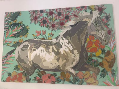 The artwork showcases a horse amidst a vibrant floral backdrop. The horse, predominantly in shades of gray, beige, and white, is depicted in motion. The surrounding flora includes sunflowers, roses, and tropical plants, all intricately detailed. The background is a light mint green. The artwork appears to be a painting.