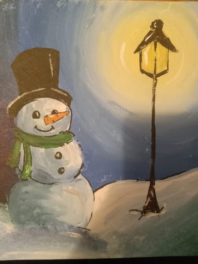 The image is a painting of a snowman standing in a snowy landscape next to a lamppost. The snowman is wearing a brown top hat and a green scarf. It has a carrot nose and two black eyes and buttons. The lamppost is lit with a yellow glow, casting a light on the surrounding snow. The background is a gradient of blue and yellow, suggesting a nighttime or dusk scene. The painting appears to be done in an impressionistic style with visible brushstrokes. There is no indication of the city of Kielce, Poland, or any specific location.