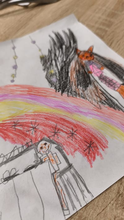A colored pencil drawing on white paper depicts a stylized, cartoonish figure with dark hair and an orange fox-like face, wearing a pink and white outfit. The figure is positioned behind a red, yellow, and pink rainbow. Below the rainbow, a grey structure resembling a building or monument is drawn with orange and black markings. Several star-like shapes are scattered across the red section of the rainbow. The drawing is placed on a wooden surface. There is no identifiable location in the city of Malaya Shil'na, Russia.