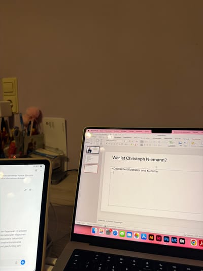 The image captures a workspace in Haßloch, Germany, featuring a laptop and a tablet. The laptop, likely a MacBook, is open and displaying a Microsoft PowerPoint presentation in a brightly lit screen. The presentation slide is titled "Wer ist Christoph Niemann?" (Who is Christoph Niemann?), with a bullet point stating "Deutscher Illustrator und Künstler" (German Illustrator and Artist). The PowerPoint interface shows various menu options and ribbon tabs in German, including "Datei" (File), "Bearbeiten" (Edit), "Ansicht" (View), "Einfügen" (Insert), "Format", "Anordnen" (Arrange), and "Extras". The macOS dock is visible on the right side of the screen, featuring icons for applications such as Mail, Safari, Messages, Photos, App Store, Adobe Illustrator (Ai), InDesign (Id), Photoshop (Ps), Lightroom Classic (LrC), Bridge (Br), and Google Chrome. The status bar indicates "Folie 3 von 3 Deutsch (Deutschland)" (Slide 3 of 3 German (Germany)).

Below the laptop, a tablet (possibly an iPad) is positioned, displaying a document or notes, also in German. Visible text fragments include "...rholen sich einige Punkte. Eine gute neue Informationen bringen." (some points are recovering. Bring good new information.) and "...der Gegenwart. Er arbeitet internationalen Magazinen. Besonders bekannt ist kreative Kunstwerke und gleichzeitig sehr..." (of the present. He works for international magazines. Particularly known are creative artworks and at the same time very...). A battery or zoom indicator shows "66%".

The setting appears to be indoors, possibly an evening scene, with warm artificial lighting illuminating the devices. A power outlet is visible on the wall behind the tablet, and various desk accessories and cables are clustered between the devices.