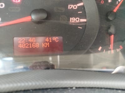 The media file shows a close-up of a car's dashboard, focusing on the instrument cluster. The primary subjects are the various gauges and displays that provide information to the driver. These include a speedometer with markings up to 190, a temperature gauge, and a digital display screen. The digital screen shows the time as 22:46 and the odometer reading as 402168 KM, along with an external temperature of 41°C. There are also warning lights and indicators, such as a red light at the top left that appears to be a brake warning or similar, and the word "STOP" illuminated. The scene is dark, suggesting it is nighttime, and the car appears to be stationary. The dashboard is dusty, which is a notable detail. The setting is the interior of a vehicle. The activity is implied to be the car being parked or having recently completed a journey, given the time and mileage displayed. There are no people visible. The visible text includes "STOP", "170", "190", "IGOD 200 KI", "22:46", "402168 KM", and "41°C", along with a symbol that looks like a water droplet or engine temperature indicator.