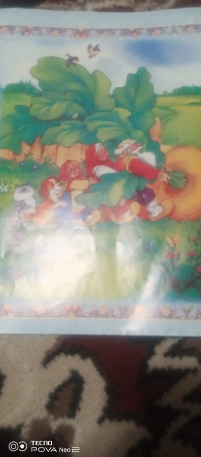 This media file depicts a whimsical illustration with a fantasy theme. The central subjects are a group of small, gnome-like figures engaged in an activity that appears to be pulling a giant, round orange object, likely a radish or turnip, from the ground. One figure, resembling an elderly man with a white beard and red hat, is particularly prominent. Beside them, a cat and a dog observe the scene. The setting is a vibrant, green landscape with large, leafy plants, a wooden fence, and a field in the background under a blue sky with two birds in flight. A decorative border with floral motifs runs along the top and bottom of the illustrated area.
The overall mood is playful and cheerful, suggesting a joyous harvest or a community effort. There are no explicit cues for the time of day or weather, but the bright lighting and blue sky imply a pleasant daytime. The location context provided is Tahmach, Uzbekistan, but this is not visually evident within the artwork itself.
The bottom portion of the image shows a close-up of a patterned carpet or fabric. Overlaid on this fabric is a logo that reads "TECNO POVA Neo 2" with a circular icon. This text is a watermark or branding from the device used to capture the image, and not part of the illustrated scene.
