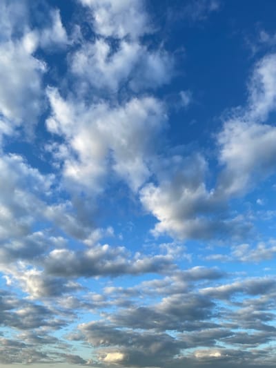 The image depicts a sky filled with a mix of white and gray clouds against a vibrant blue sky. The clouds are scattered across the frame, with some appearing puffy and bright, suggesting sunlight is hitting them from above. Other clouds are darker and more diffused, indicating they might be thicker or further away. The overall impression is of a dynamic sky, possibly during the daytime with varying cloud cover. There are no visible landmarks or man-made structures that would specifically indicate the location within Турово, Russia. The image focuses solely on the atmospheric conditions above.