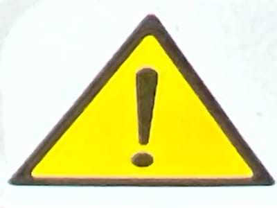 A yellow triangular warning sign with a dark outline features a dark brown exclamation point in the center. The sign is set against a white background, suggesting it might be a digital representation or a printed sticker. The image does not contain any elements that place it within the city of Lanžhot, Czechia.