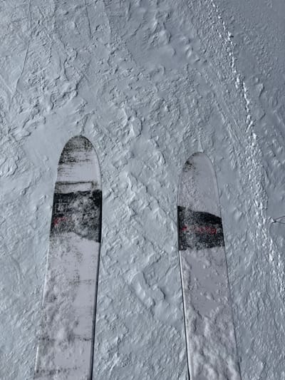 The image is a high-angle shot of two skis resting on a snow-covered surface. The skis appear to be partially buried in the snow, with only the tips and a section of the ski surface visible. The snow is uneven and textured, suggesting a natural, untracked landscape.
The location, Puy-Saint-André, France, implies that the skis are likely in a mountainous or alpine environment, suitable for skiing. The absence of any other objects or people in the frame suggests a remote or isolated setting. The image conveys a sense of solitude and the potential for outdoor recreational activity, specifically skiing, in a natural, snowy environment.
