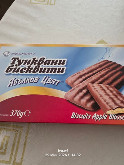 The image shows a close-up of a box of "Tunkvani biskviti" (Tunable Biscuits) with an apple blossom flavor, manufactured by "Balgarska Zahar" (Bulgarian Sugar). The box features an image of several chocolate-covered biscuits. Text on the box indicates a net weight of 370g and the English translation "Biscuits Apple Blossom". The box is placed on a white tablecloth with a floral pattern. In the bottom right corner of the image, there is a watermark that reads "ivo.wf 29 юни 2026 г. 14:32". The city of Chal, Bulgaria, is not visible or mentioned in this image.