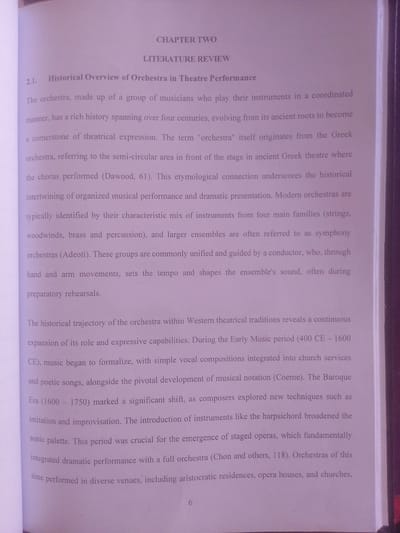 The media file is a close-up shot of an open book, showing text on its pages. The text is printed in a light, possibly grey or faded ink, against a white background. The book appears to be a non-fiction work, likely academic, given the chapter title "CHAPTER TWO" and subsection "2.1. Historical Overview of Orchestra in Theatre Performance". The content discusses the history and evolution of orchestras, mentioning musical periods like "Early Music period" and "Baroque Era," and referencing musical instruments and composers. There is a page number "6" visible at the bottom of the right-hand page. The lighting suggests an indoor environment, likely a well-lit room, with no specific time of day or weather conditions indicated. No people, specific objects other than the book, or a distinct scene are depicted; the focus is solely on the printed text. The location context of Magajin Gari, Nigeria, is not discernible from the image itself.