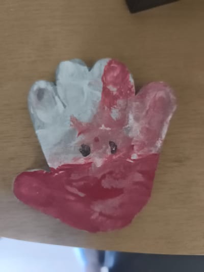 The image shows a handmade, hand-shaped object painted in red and white, with two black dots for eyes. The object is placed on a wooden surface, possibly a table. There is no indication of the city of Eitorf, Germany, within the image itself or its context.