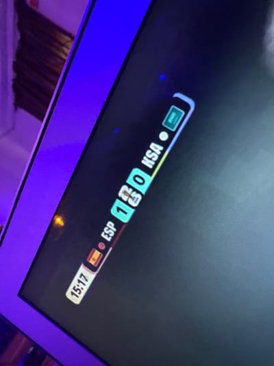 The image shows a close-up of a screen displaying a sports match score. The score indicates that Spain (ESP) is playing against Saudi Arabia (KSA) with a score of 1-0. The time displayed is 15:17. The screen is framed by a purple light, suggesting it might be a gaming setup or a scene with colored lighting. There are no people or specific environmental details visible beyond the screen and its framing. The location of Laminga, Nigeria is not depicted or suggested in the image.
