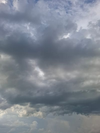 The image depicts a cloudy sky over the rural area of Авангард ауылдық округі, Kazakhstan. The sky is filled with a mix of dark, heavy storm clouds and lighter, wispy clouds, suggesting overcast or potentially rainy weather. There are no visible people, structures, or distinct geographical features that would indicate a specific location within the village, only the vast expanse of the sky. The focus is entirely on the atmospheric conditions, with the clouds dominating the frame.
