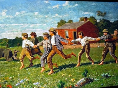 This painting depicts six young males, ranging from early to late adolescence, running barefoot across a verdant field under a partially cloudy blue sky. The individuals are arranged in a horizontal line, holding hands and moving from left to right, suggesting participation in a group game or activity.

From left to right:
1.  The first individual wears a white shirt with brown suspenders and brown trousers.
2.  The second wears a patterned cap, a dark jacket, and grey trousers.
3.  The third wears a wide-brimmed hat, a dark jacket over a light shirt, and brown trousers.
4.  The fourth wears a light shirt with suspenders and brown trousers.
5.  The fifth wears a dark patterned cap, a dark patterned jacket over a light shirt, and dark trousers.
6.  The sixth wears a wide-brimmed hat, a brown jacket, and brown trousers.
All six are barefoot, with their limbs in dynamic poses characteristic of running.

The immediate foreground is a green grassy field dotted with small white, yellow, and red wildflowers. In the midground, to the far left, two dark-colored animals are visible; one appears to be a large, stocky animal, possibly a boar, facing left, with a smaller, dog-like animal positioned in front of it, facing right. To the right of the running figures, a rustic, single-story red wooden building with a dark grey shingled roof and a brick chimney on its left side stands prominently. The building features one visible window with white frames and a dark rectangular doorway. A line of dense green trees forms the horizon behind the building and the figures. The sky is a light blue, populated with scattered white cumulus clouds.

The rural scene is depicted within what is specified as the city of Reus, Spain.