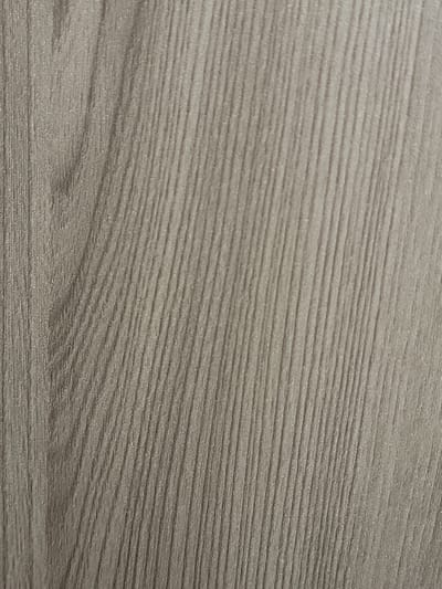 The image displays a close-up, overhead view of a textured surface with a wood grain pattern. The color of the surface is a muted, grayish-brown, with darker lines running diagonally from the bottom left to the top right, representing the wood grain. The texture appears to be matte and slightly rough, mimicking natural wood. There are no people, objects, or any discernible environmental features present in the image. The image's location in Zlatopil, Ukraine, is not visually represented or implied by the content of the photograph.