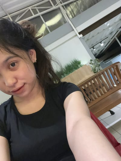 A selfie of an individual with dark hair, wearing a black shirt. The background includes a window with white frames, some greenery, and a wooden chair. The specific location in the city of Magelang, Indonesia is not discernible from the image.