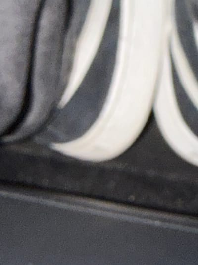 The image is a close-up, abstract shot of a textured surface with dark gray and white elements. The texture appears to be a stylized decorative pattern, possibly carved or molded, with rounded, flowing shapes. The lighting creates shadows and highlights that emphasize the depth and form of the material. The lower portion of the image shows a flatter, matte dark gray surface, which could be a base or surrounding area. The image does not contain any discernible elements that would allow for identification of a specific city, location, or any environmental context such as Ödsmål, Sweden.