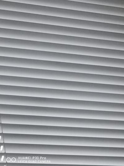 The image shows a close-up, high-angle view of closed horizontal blinds, which are predominantly white or light gray. The blinds create a repetitive pattern of parallel lines with subtle shadows between them. In the bottom left corner, the text "HUAWEI P30 Pro LEICA QUAD CAMERA" is visible, indicating that the image was captured using this specific device. The lighting appears to be uniform, suggesting an indoor setting or a heavily overcast day. There are no people, animals, or significant environmental details visible beyond the blinds themselves. The overall impression is of a simple, abstract texture. The city of Bad Oeynhausen, Germany, is not depicted in this image.