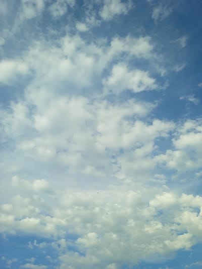A sky filled with white clouds is visible, set against a clear blue sky. There are no people, subjects, objects, or actions depicted in the image. The environment is an outdoor sky scene. The location is Taran-Bazar, Kyrgyzstan.
