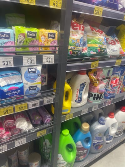 The image depicts a retail shelf stocked with hygiene and cleaning products, likely in a supermarket. The products are predominantly packaged in plastic containers and bags, with various brands and types of items visible, including sanitary pads, laundry detergent, and washing gel. Labels and pricing information are visible in Ukrainian. The overall lighting suggests an indoor commercial setting. The products are arranged on multiple shelves, creating a densely packed display. The specific location of Гожули, Ukraine, is not directly discernible from the visual information presented in the image itself, but it is contextually provided.