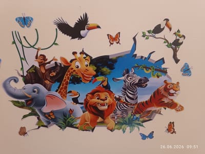 This media file is a photograph of a wall mural depicting cartoon animals in a jungle-like setting. The mural features an elephant, giraffe, lion, tiger, zebra, monkey, toucans, a snake, and various butterflies. The animals appear to be bursting through a ripped wall, with a blue sky and some foliage visible behind them. The overall tone is cheerful and playful. There are no people visible in the image. The time and date stamp in the bottom right corner indicates "26.06.2026 09:51," suggesting the photograph was taken in the morning. Location cues are limited to "Strovolos, Cyprus" in the prompt. The mural is likely a decorative element in a room, possibly a child's bedroom or a play area.