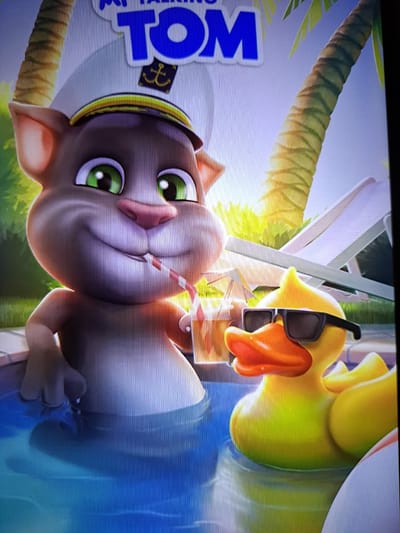 The image is a digital illustration featuring cartoon characters in a swimming pool. On the left, a gray cat wearing a sailor's hat and a red and white striped straw is drinking from a cup. To the right of the cat, a yellow rubber duck wearing sunglasses is floating in the water. In the background, palm trees and lounge chairs are visible, suggesting a tropical or poolside setting. The text "MY TALKING TOM" is displayed at the top of the image. There is no discernible connection to the city of Pervomaisk, Ukraine.