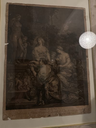 Framed antique print depicting a classical mythological scene, potentially from the 18th or 19th century. The scene features several nude or partially draped figures in a landscape setting, including what appears to be a reclining female figure in the foreground and a group of figures gathered around a stone structure or altar. The composition is intricate, with detailed rendering of drapery, anatomy, and foliage. The print has aging and damage along the edges, with visible tears and stains. There is text in the right side describing it as a "grave d'après le Tableau Original" of the city Perugia, Italy and dedicated to the Duke of Orleans.